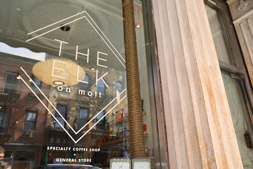 A window picturing the words "THE ELK on mott" in a light pink, thin font.